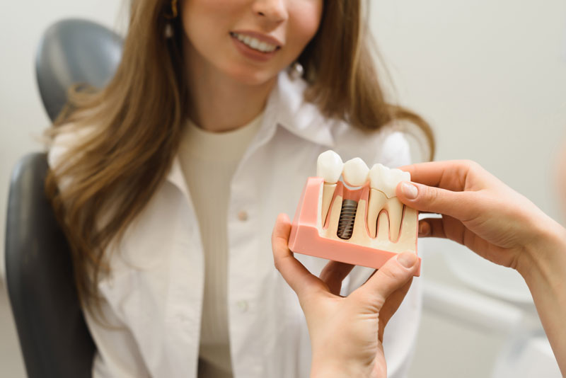 Dental Patient Getting Shown A Dental Implant Model During Her Consultation in Cambridge, OH