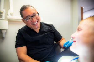 Dr. Maximo smiling at a patient after he has enhanced his smile with a professional teeth cleaning procedure.