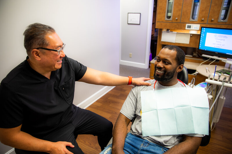 doctor franklin maximo meeting and talking to a patient thats sitting in a dental chair