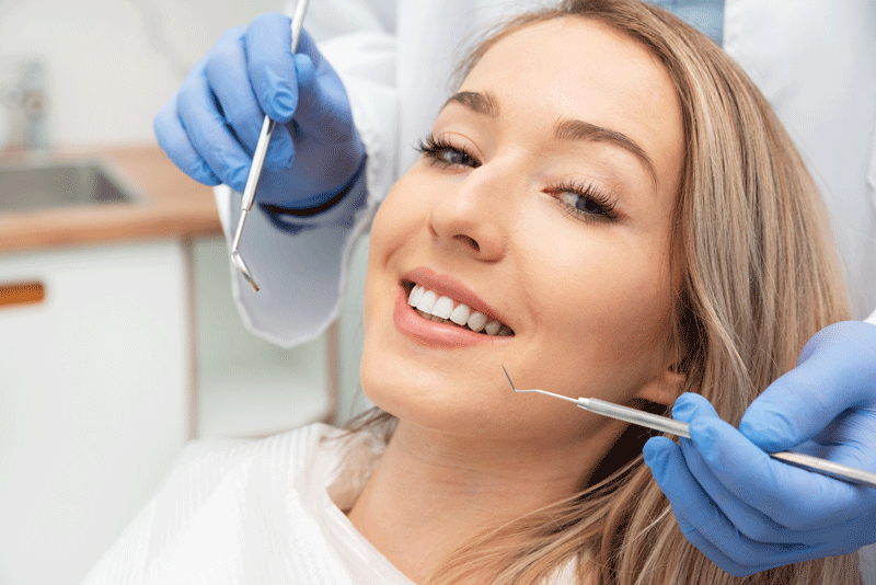 women laying in dental chair, getting mouth looking at with dental tools