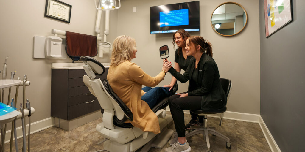 team members and Patient looking into mirror smiling